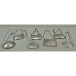 A COLLECTION OF SEVEN ASSORTED SILVER WINE & SPIRIT LABELS, various stamped shapes, with chains,