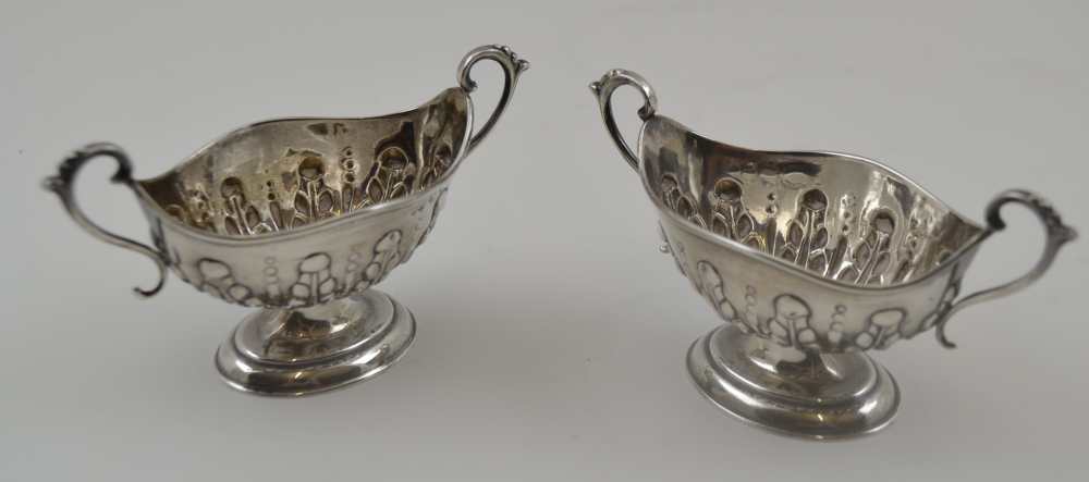 NATHAN & HAYES A PAIR OF SILVER SALTS, boat form with two handles, repousse decoration on oval