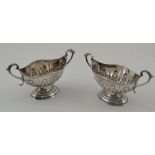 NATHAN & HAYES A PAIR OF SILVER SALTS, boat form with two handles, repousse decoration on oval