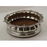 JONATHAN HAYNE A GEORGE IV SILVER BOTTLE COASTER, decorative lobed gallery, turned wood base with