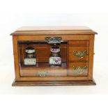 AN EDWARDIAN OAK WRITING CABINET with drop fronted glass panel, revealing drawers and two
