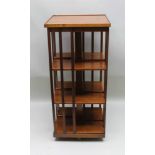 A MODERN WALNUT COLOURED FOUR-TIER REVOLVING BOOKCASE, with decoratively herring bone inlaid top,
