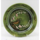 A LATE 19TH CENTURY GREEN GLAZED POTTERY SHALLOW BOWL, with tube lined and painted floral