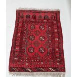 A TURKOMAN PIGEON RED GROUND WOVEN WOOLLEN FLOOR RUG featuring flowerhead and geometric bands,