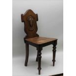 A 19TH CENTURY OAK HALL CHAIR, with standard carved shield back over solid plank seat, turned fore