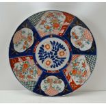A JAPANESE IMARI CERAMIC CHARGER, painted and gilded with panels of flowers on a cobalt blue ground,