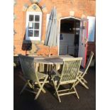 A WELL WEATHERED TEAK PATIO DINING SUITE comprising; circular twin flap table with central lazy