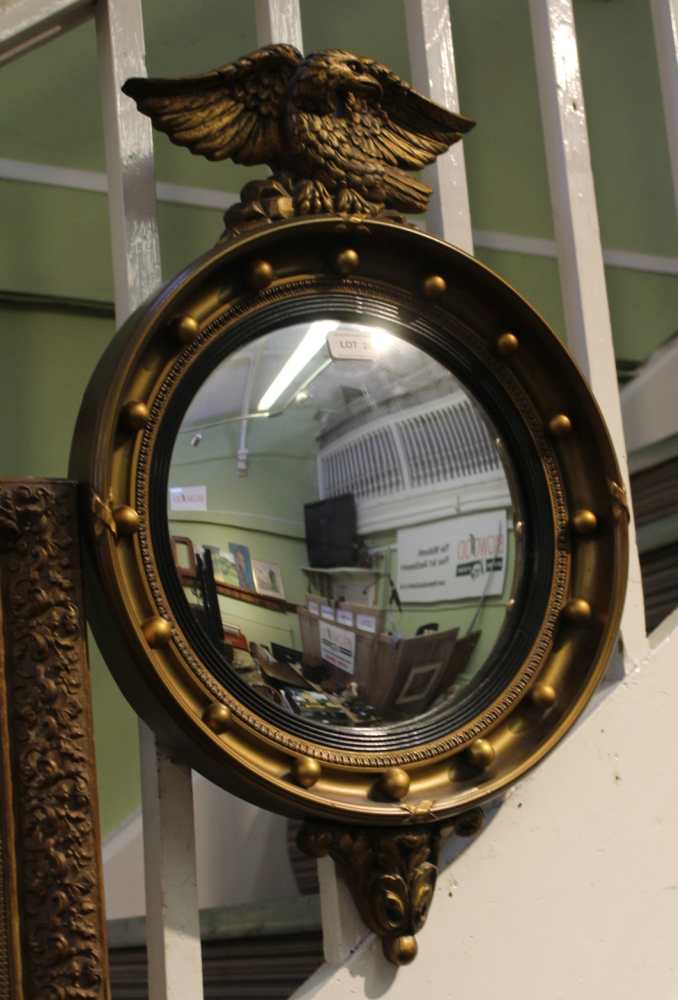 A REGENCY DESIGN GILT FRAMED CONVEX WALL MIRROR with ball frame and eagle crest, plate size; 28cm