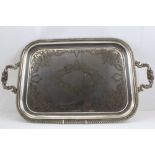 AN EDWARDIAN SILVER PLATED TEA TRAY, gadrooned rim with chased decoration, fitted with a pair of