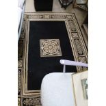 A MODERN MACHINE MADE BLACK, CREAM & GOLD FLOOR CARPET displaying architectural panels within rope