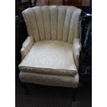 AN OLD GOLD UPHOLSTERED SHELL DESIGN BACKED ARMCHAIR