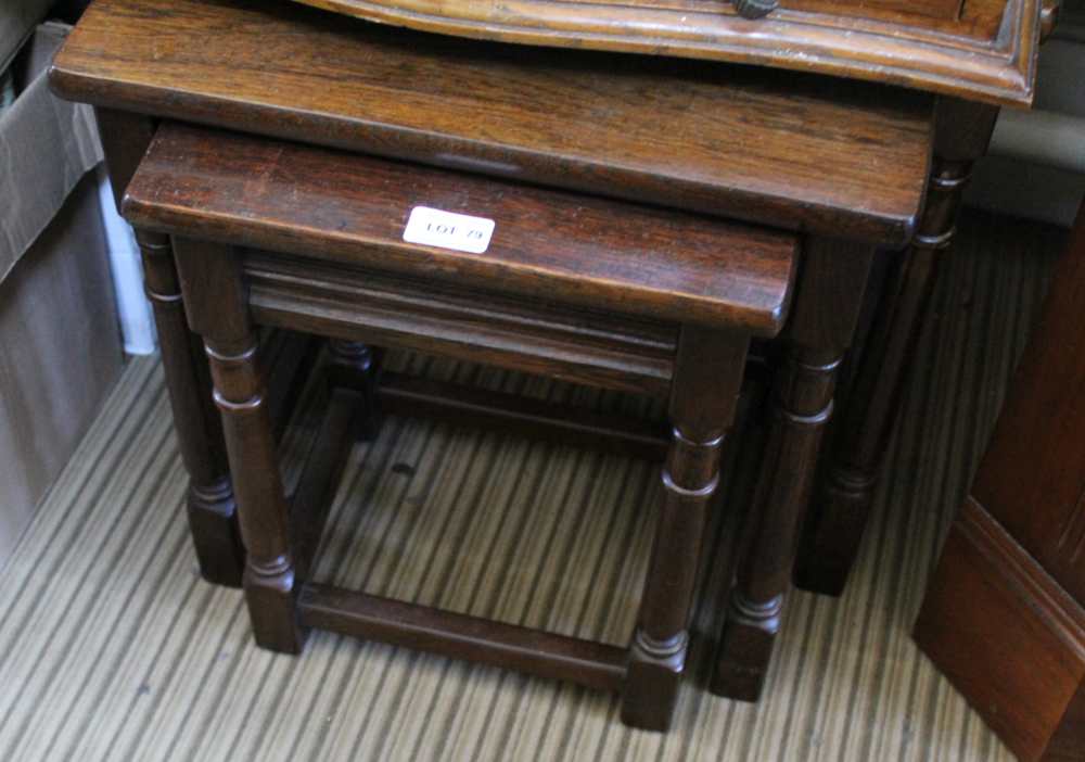 A REPRODUCTION OAK FINISHED NEST OF THREE TABLES on canon barrel legs