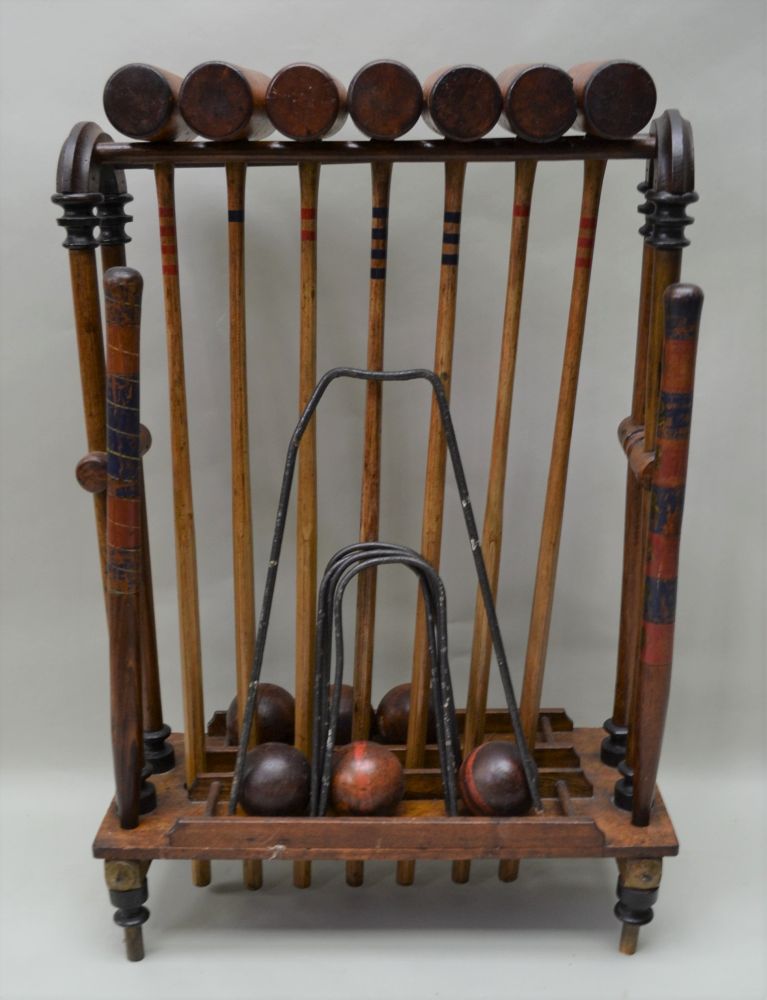 A WOODEN CROQUET SET ON STAND comprising seven mallets, six balls, two posts & five iron hoops,