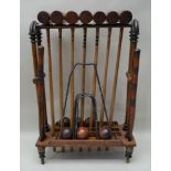A WOODEN CROQUET SET ON STAND comprising seven mallets, six balls, two posts & five iron hoops,
