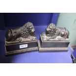 A PAIR OF PATINATED CAST RESIN RECUMBENT LIONS on plinth