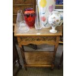 AN OAK FINISHED SIDE TABLE with part carved top & carved front drawer