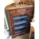 A FREESTANDING OAK CASED CORNER UNIT with plain glazed door revealing painted shelved interior