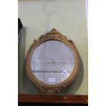 A FANCY MOULDED GILT FRAMED OVAL PLAIN PLATE WALL MIRROR