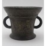 A BRONZE MORTAR, cast with two handles & bears a worn crest, 13cm high, considered to be 17th