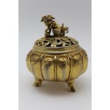 A CHINESE GILDED WHITE METAL CENSER, of lobed form, on three outswept feet, having a pierced cover