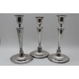 A SET OF THREE ADAM DESIGN CANDLESTICKS, on elliptical fluted bases, considered to be silver,