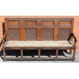 A 19TH CENTURY OAK FINISHED FANCY PANELLED BACK FOUR PERSON SETTLE, with upholstered drop-in seat