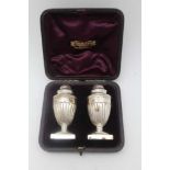 GEORGE UNITE A pair of Victorian silver peppers, of Regency Urn form, fluted bodies raised on square