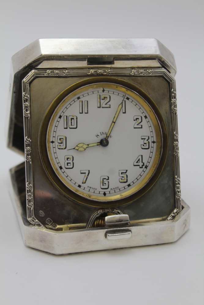 GOLDSMITHS & SIVERSMITH CO. LTD, A SILVER CASED TRAVEL CLOCK, hinged form with bounds reed edge,