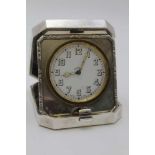 GOLDSMITHS & SIVERSMITH CO. LTD, A SILVER CASED TRAVEL CLOCK, hinged form with bounds reed edge,