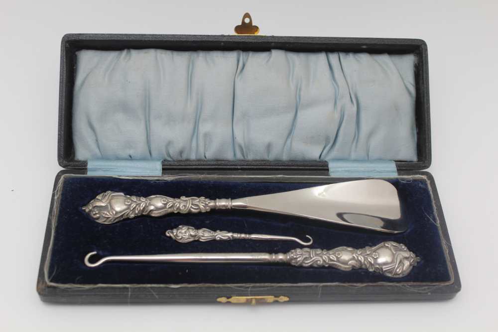 A CASED SILVER HANDLED SET, comprising shoehorn, boot & glove button hooks, embossed bird on a