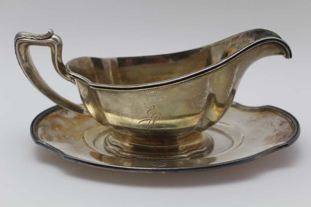 A STERLING SILVER SAUCE BOAT with stand, considered to be Gorham, Georgian design, monogrammed, 522g