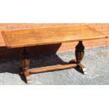 A REPRODUCTION OAK FINISHED RECTANGULAR TOP REFECTORY STYLE TABLE supported on two carved large