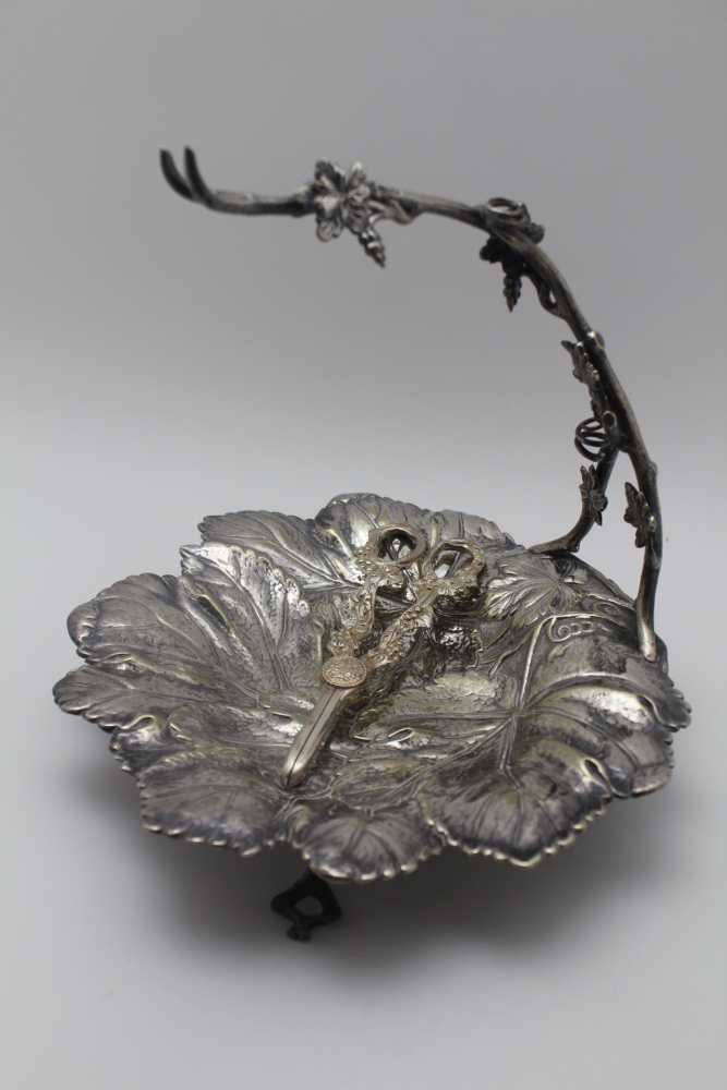 A VICTORIAN SILVER PLATED GRAPE DISH, moulded leaf form with vine arm to support the bunch, raised