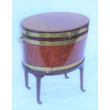 A 19TH CENTURY MAHOGANY CELLARETE OF OVAL BRASS BANDED FORM with hinged cover & side handles, raised