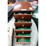 A MAHOGANY COLOURED FIVE DRAWER JEWELLERY BOX with contents, masks, paperweight