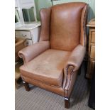 A MODERN TANNED LEATHER UPHOLSTERED WING BACK DEEP SEATED ARMCHAIR, with decorative stud work, on