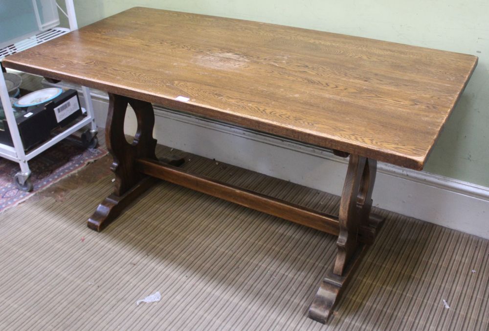 A REPRODUCTION OAK FINISHED RECTANGULAR TRESTLE TYPE TABLE on pierced shaped plank supports