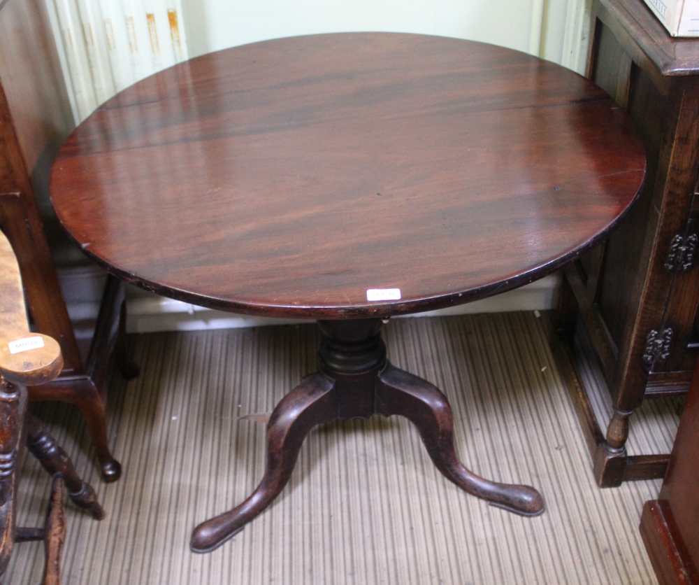 A 19TH CENTURY MAHOGANY CIRCULAR TILT TOP TABLE on turned column and three outswept legs