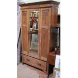 AN ART NOUVEAU DESIGN OAK WARDROBE having single insert bevelled mirror door over full width shoe