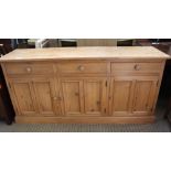 A 20TH CENTURY PINE DRESSER/SIDEBOARD UNIT with three inline drawers, over three cupboard doors