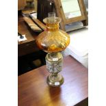 A BRASS BASED OIL LAMP with amber coloured shade