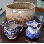 A WOVEN FIBRE BASKET CONTAINING TWO POTTERY JUGS, one 19th, one 20th century