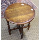 A SMALL OAK CIRCULAR TOPPED FOLDING TABLE on barley twist legs