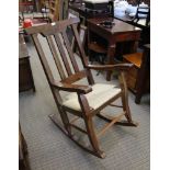 AN IMPORTED HARDWOOD SLAT BACK ROCKING ARMCHAIR, with rush work seat