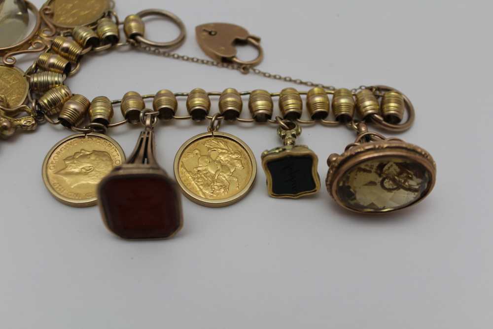 A YELLOW METAL CHARM BRACELET set with four framed full sovereigns, and five fob seals, some - Image 2 of 4