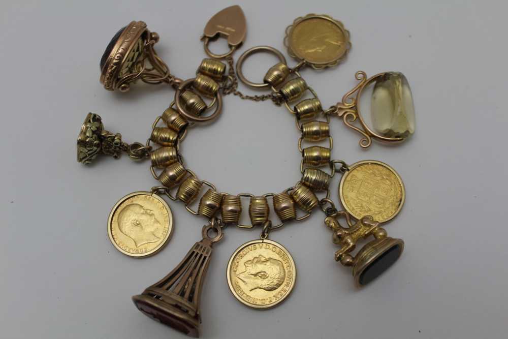 A YELLOW METAL CHARM BRACELET set with four framed full sovereigns, and five fob seals, some - Image 4 of 4