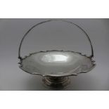 BARKER BROTHERS SILVER LTD, A SILVER SWING HANDLE CAKE SERVING DISH, wavy rim with swing handle on