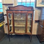 A turn of the century mahogany bow fronted display cabinet with inlay decoration and lead glazed