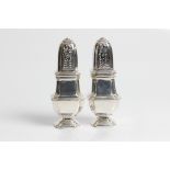A pair of silver pepper pots with marks for Britannia London 1912 and 1913 and Lionel Alfred