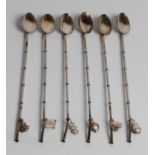 A set of six silver teaspoons in a box, each with a bamboo form handle and a charm at the end,